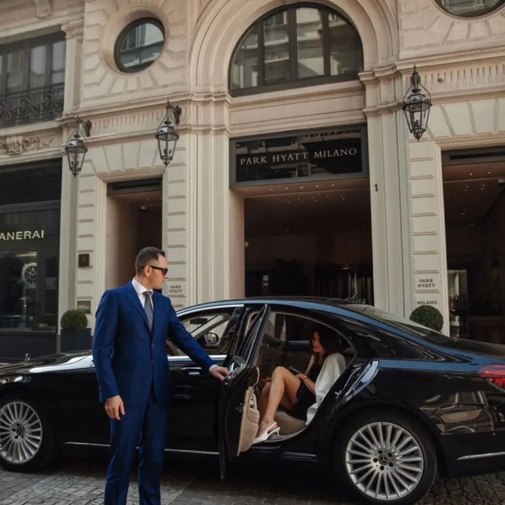 Professional driver holding door open for talent at hotel entrance